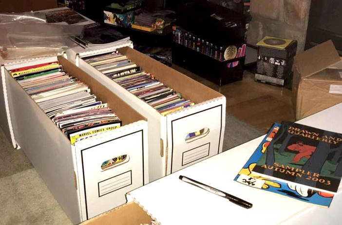 Person writing notes while sorting comics